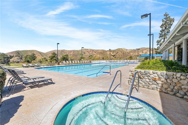 community pool featuring a patio, a community hot tub, and a mountain view