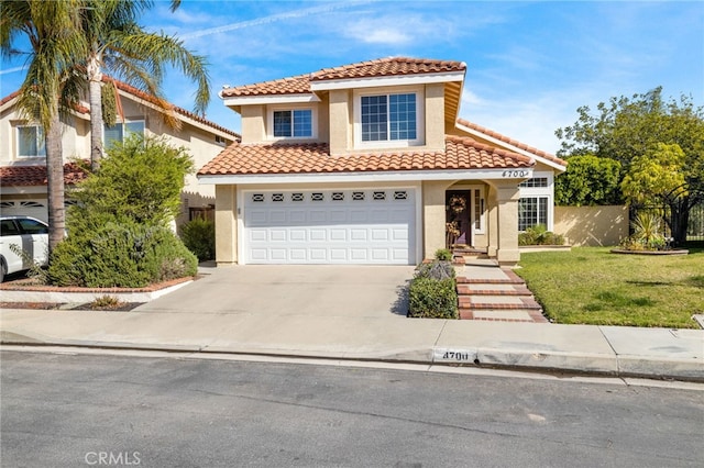 mediterranean / spanish house with fence, a tile roof, stucco siding, a garage, and driveway