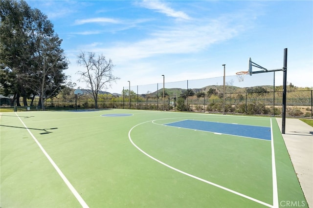 view of sport court featuring a mountain view, community basketball court, and fence