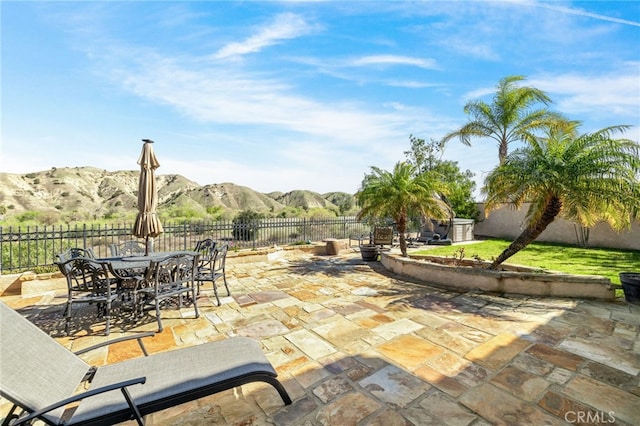 view of patio featuring outdoor dining area, a fenced backyard, and a mountain view