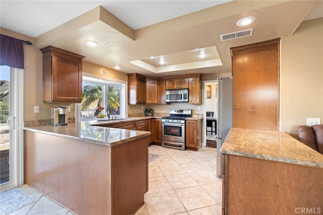 kitchen with visible vents, light tile patterned floors, appliances with stainless steel finishes, a peninsula, and a raised ceiling