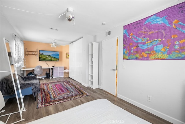 bedroom featuring visible vents, baseboards, wood finished floors, and built in study area