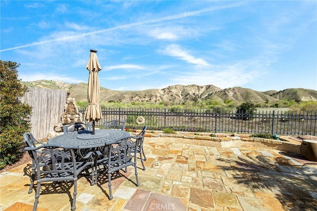 view of patio with outdoor dining space, a mountain view, and fence