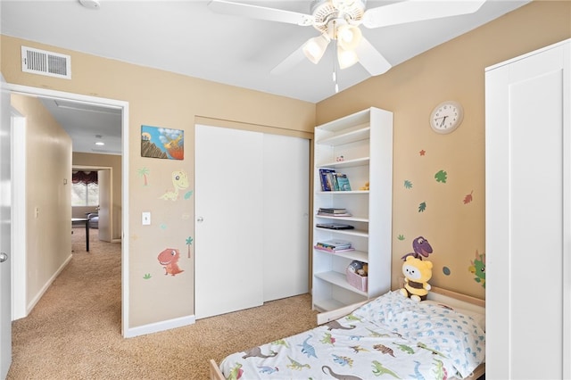 bedroom with visible vents, a ceiling fan, a closet, baseboards, and light colored carpet