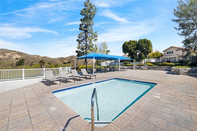 view of swimming pool with a mountain view, a patio area, and fence