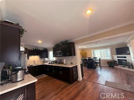 kitchen with light countertops, appliances with stainless steel finishes, dark wood-style flooring, and crown molding