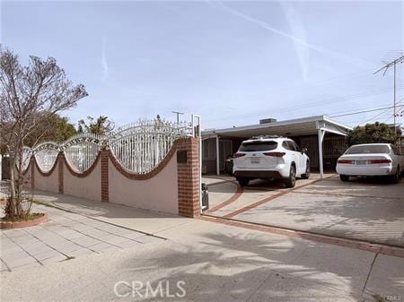 view of front facade with driveway, an attached carport, fence, and a gate