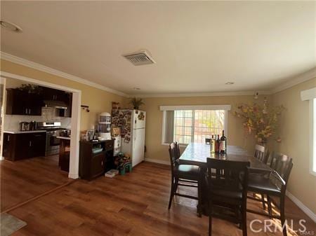 dining area with ornamental molding, wood finished floors, and visible vents