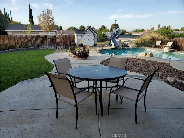view of patio / terrace with outdoor dining space, a fenced backyard, an outdoor structure, a fenced in pool, and a storage unit