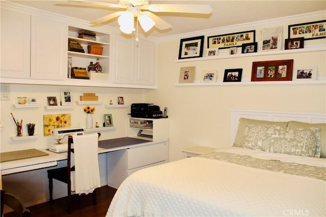 bedroom featuring ceiling fan, dark wood-type flooring, crown molding, and built in study area