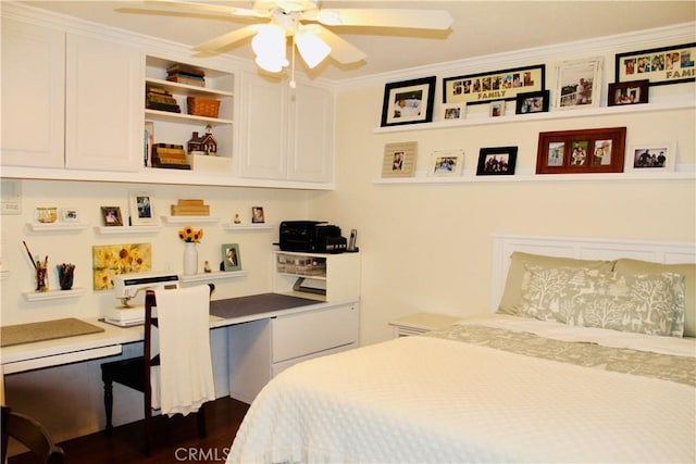 bedroom with ceiling fan, crown molding, dark wood-style floors, and built in desk