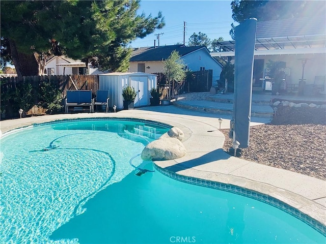 view of swimming pool with a fenced in pool, an outbuilding, a storage shed, a patio area, and fence