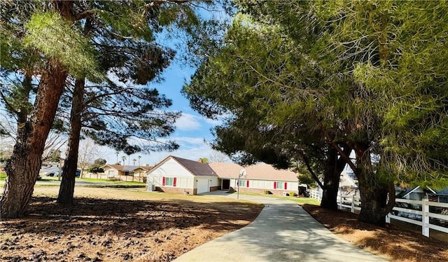 ranch-style home featuring driveway and fence