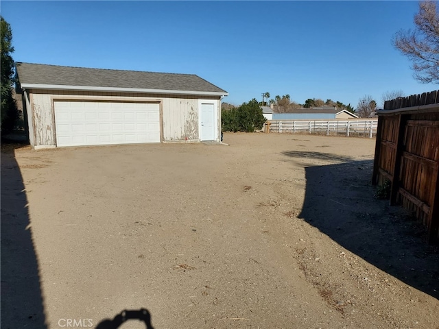 view of yard featuring a garage, fence, and an outdoor structure