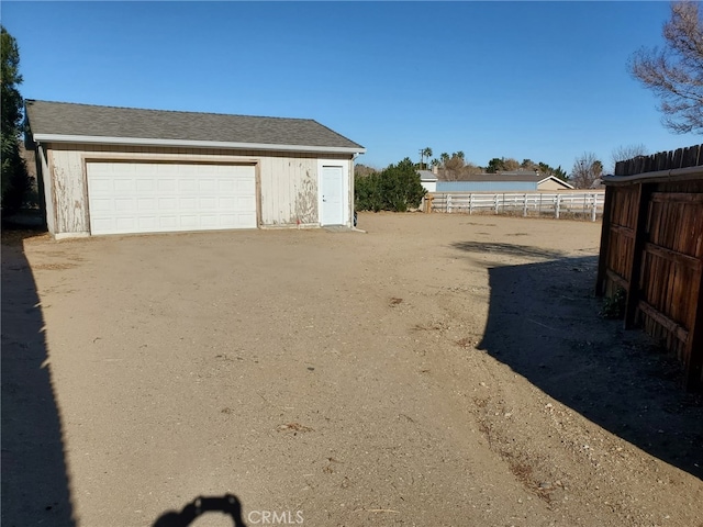 view of yard with an outdoor structure, a detached garage, and fence