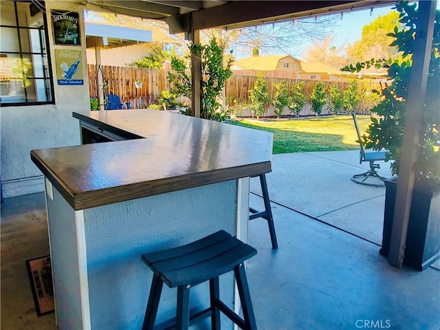 view of patio featuring fence and outdoor dry bar