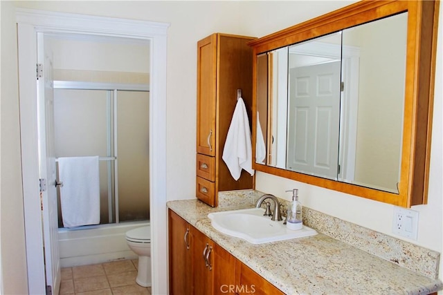 full bathroom featuring enclosed tub / shower combo, vanity, toilet, and tile patterned floors