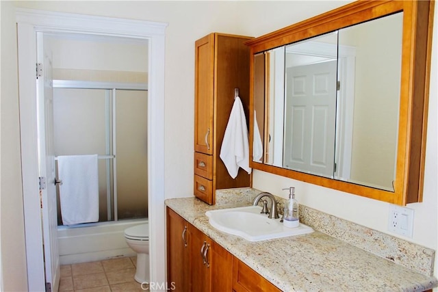 bathroom featuring combined bath / shower with glass door, toilet, vanity, and tile patterned floors