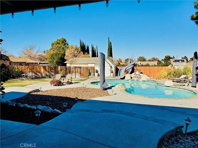 exterior space featuring a patio, a water slide, an outdoor fire pit, a fenced backyard, and a fenced in pool