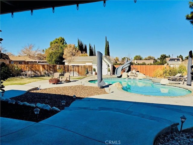 view of swimming pool featuring a fenced backyard, a water slide, a fenced in pool, and a patio