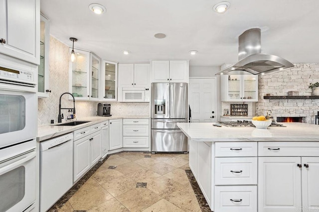 kitchen with white appliances, a sink, white cabinets, tasteful backsplash, and island exhaust hood