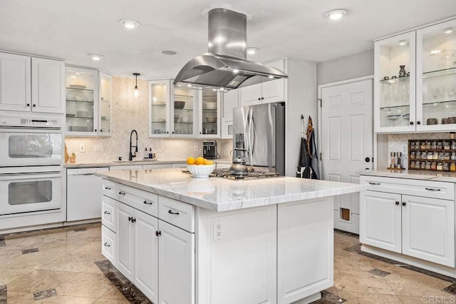 kitchen with stainless steel appliances, white cabinets, a sink, and island range hood