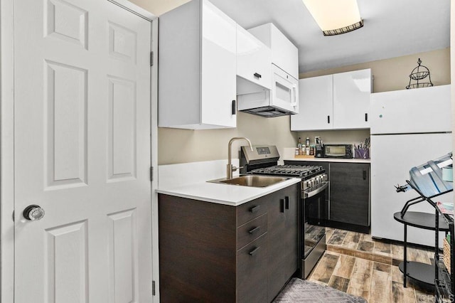 kitchen with white appliances, a sink, light wood-style floors, white cabinets, and light countertops