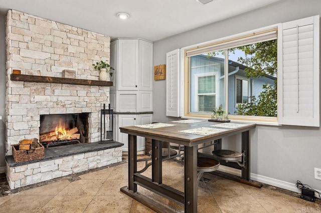 dining space with stone finish flooring, a fireplace, and baseboards