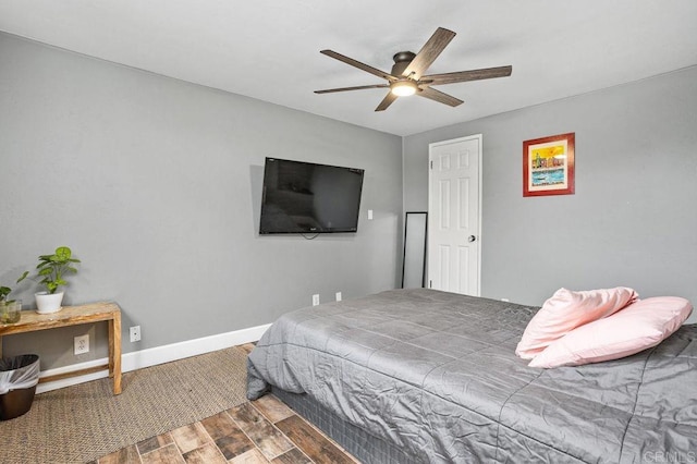 bedroom with a ceiling fan, baseboards, and wood finished floors