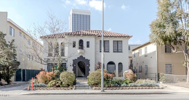 view of front of home with a tile roof, fence, and stucco siding