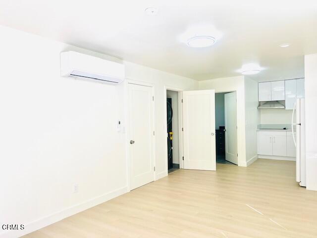 741 S Curson Ave, Los Angeles, CA 90036 - empty room with baseboards, light wood-style flooring, and a wall mounted AC