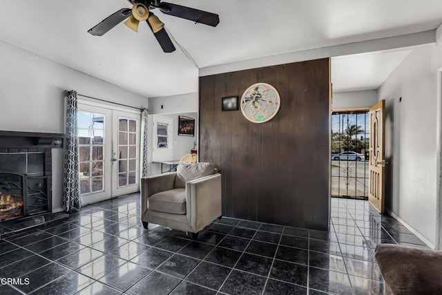 living area with baseboards, french doors, a tiled fireplace, and a healthy amount of sunlight