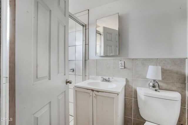 bathroom with toilet, tile walls, and vanity