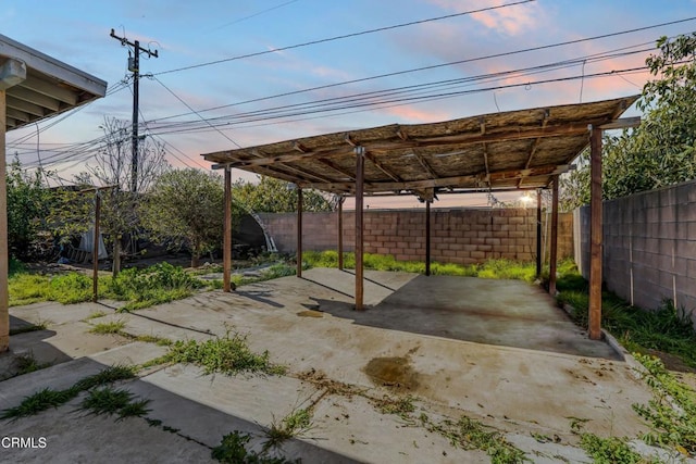 parking at dusk featuring a carport and a fenced backyard