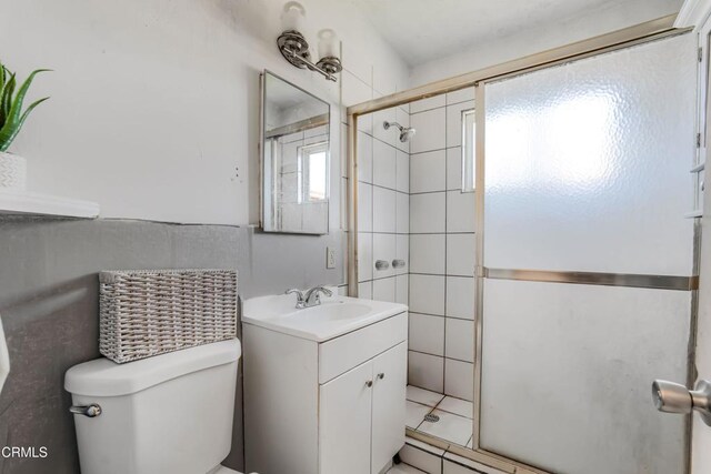 bathroom with a shower stall, toilet, and vanity