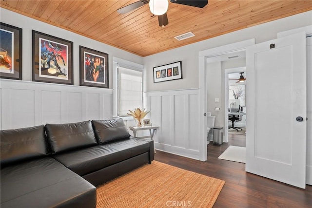 living room with a decorative wall, dark wood-type flooring, wood ceiling, visible vents, and a ceiling fan