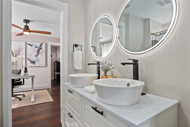 bathroom featuring a textured wall, wood finished floors, a sink, and visible vents