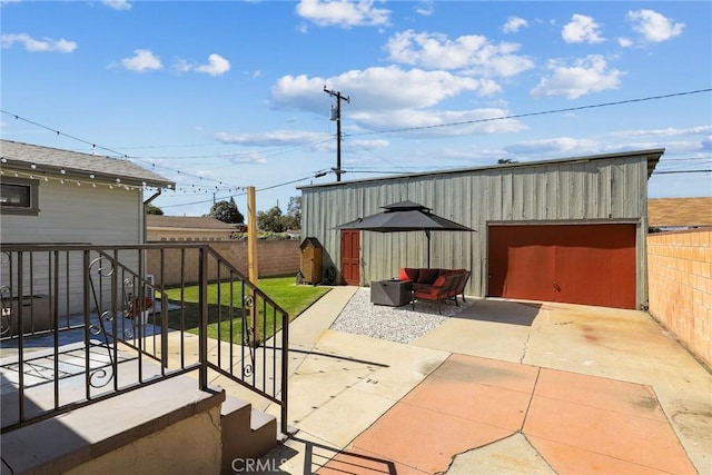 view of patio with a garage, concrete driveway, an outdoor structure, and a fenced backyard