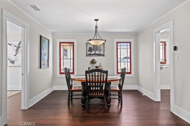 dining area featuring ornamental molding, dark wood-style flooring, visible vents, and baseboards