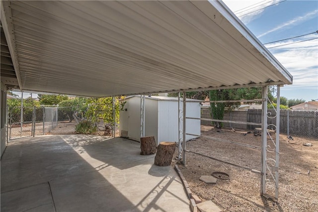 view of patio / terrace featuring an outbuilding, a storage shed, fence, driveway, and a carport