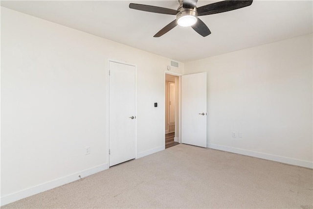 interior space featuring light carpet, ceiling fan, visible vents, and baseboards