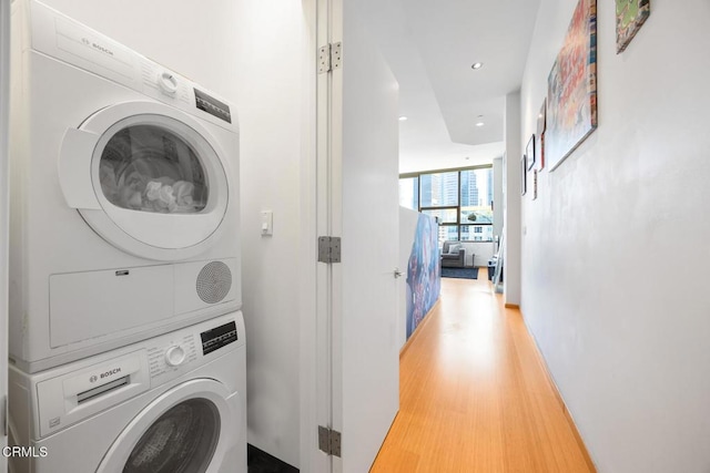 clothes washing area featuring laundry area, recessed lighting, light wood-style flooring, and stacked washer / drying machine