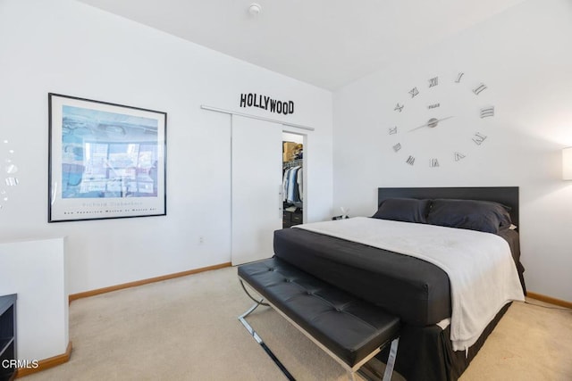 bedroom with a spacious closet, baseboards, a closet, and light colored carpet