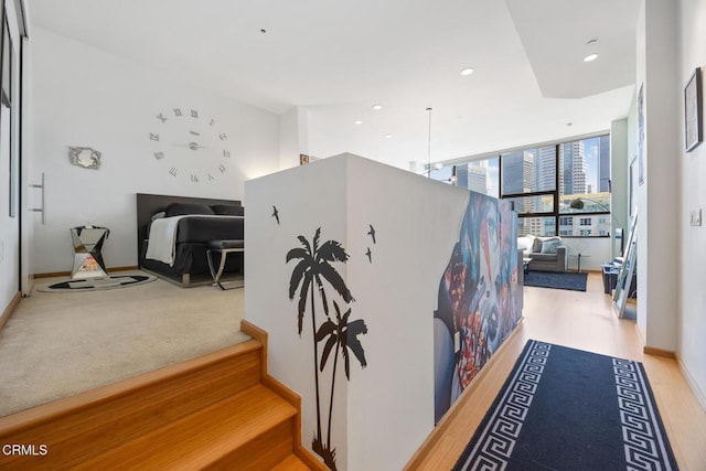 hall featuring a wall of windows, recessed lighting, baseboards, and wood finished floors