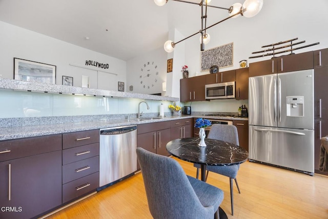 kitchen featuring appliances with stainless steel finishes, a sink, light wood-style flooring, and dark brown cabinetry