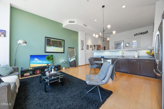 living room featuring an inviting chandelier, light wood-style flooring, visible vents, and recessed lighting