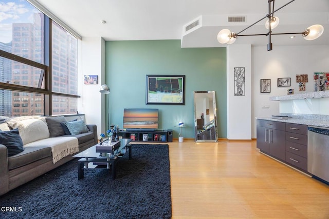 living room with floor to ceiling windows, visible vents, and light wood-style flooring