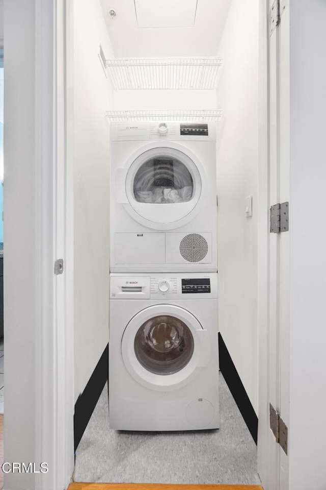 washroom featuring laundry area, baseboards, and stacked washer and clothes dryer