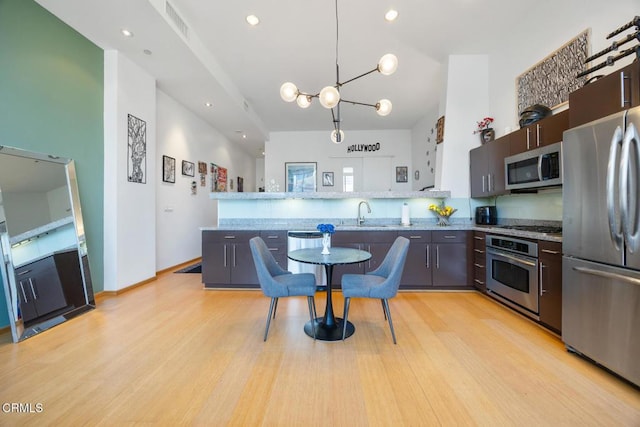 1100 Wilshire Blvd Unit 1808, Los Angeles, CA 90017 - kitchen with appliances with stainless steel finishes, a chandelier, light wood-type flooring, a peninsula, and recessed lighting