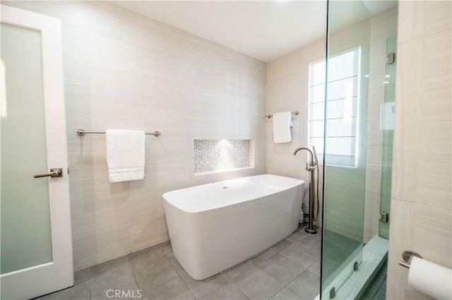 bathroom featuring a soaking tub, tile patterned flooring, tile walls, and a shower stall